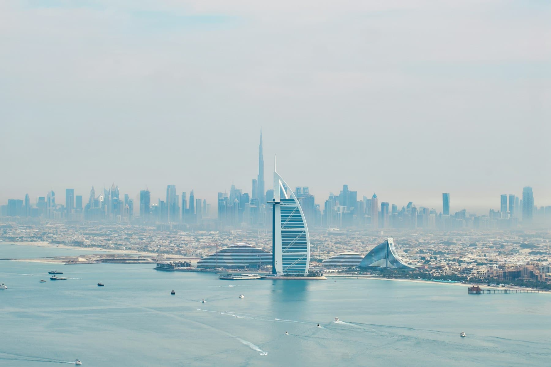 The Burj Al Arab in front of the Downtown Dubai skyline by day